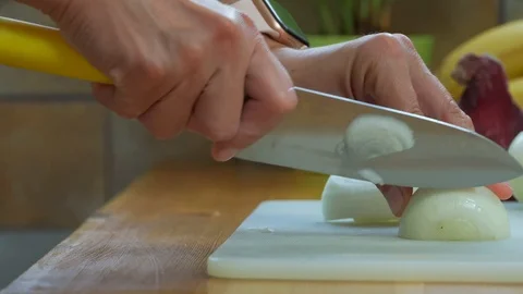 Close-up view of woman's hands is cutting onion on cutting board Stock Footage 114875285