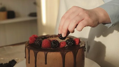 Close up view of the woman's hands decorating cake with fresh berries Stock Footage 125827132