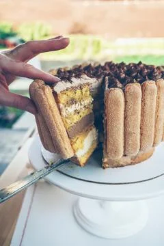 Close up view of womans hands getting slice of freshly cut tiramisu cake Stock Photos