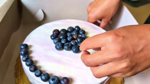 Close-up view of woman's hands with pink nails placing blueberry fruit on Stock Footage 280251868