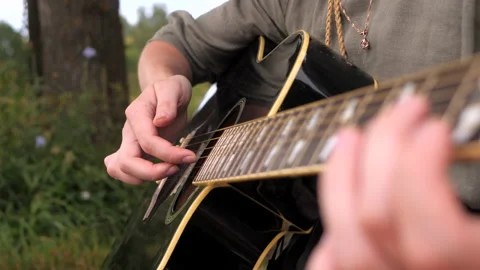Close up view of woman's hands playing the guitar. Outdoors in summer. Stock Footage 148323216