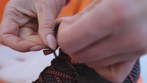 Close up view of woman's hands tie shoelaces on her sneakers. Stock Footage 124329874