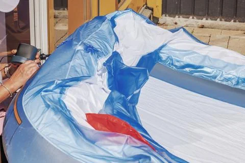 Close-up view of a woman's hands using an electric air pump to inflate a pool Stock Photos