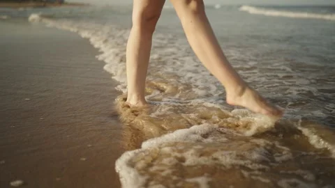 Close-up view of a woman's legs and bare feet walking on a sandy beach. Gen.. Stock Footage 343681941