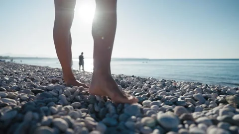 Close-up view of woman's legs walking on the pebble beach. Stock Footage 245724246