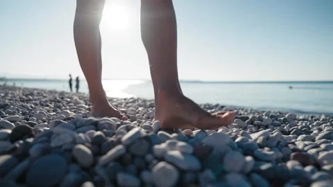 Close-up view of woman's legs walking on the pebble beach. Stock Footage 246043918