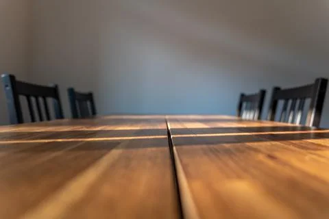 Close view of wooden dining table. Soft background with large copy space. Stock Photos