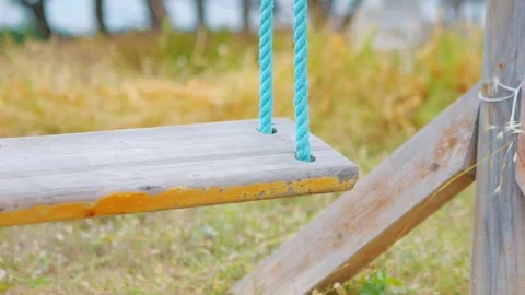 A close-up view of a wooden swing gently moving in slow motion 60fps Stock Footage 290097316