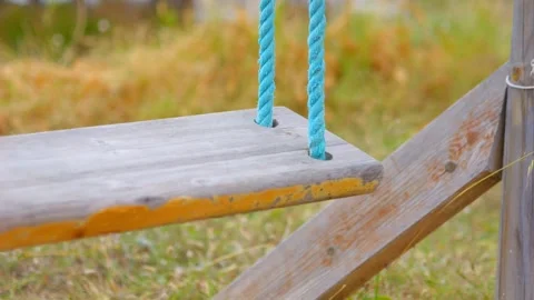 A close-up view of a wooden swing gently moving in slow motion 60fps Stock Footage 290097318