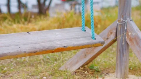 A close-up view of a wooden swing gently moving in slow motion 60fps Stock Footage 290097336