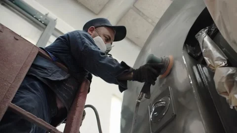 A close-up view of a worker in overalls and a respirator is grinding the Stock Footage 196357164