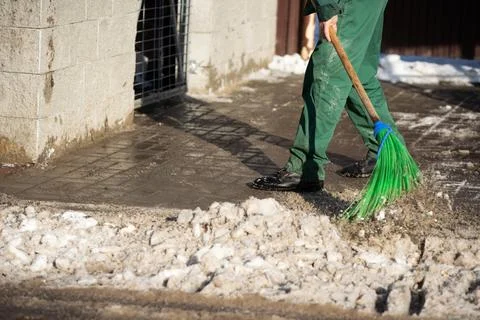 A close-up view as a worker sweeps the pavement out of loose snow Foto stock
