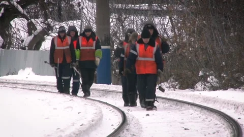 Close view of workers in uniform walking along railway tracks in winter. Stock Footage 135396071