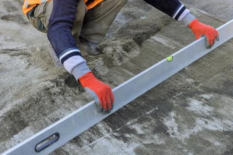 Close view of working man holding a level tool in leveling preparation on a s Stock Photos