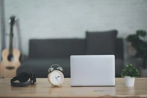 Close up view of worktable with laptop,  headphone, clock, acoustic guitar an Stock Photos