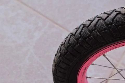 Close up view of worn black rubber tire tread and pink wheel rim on old kid.. Stock Photos