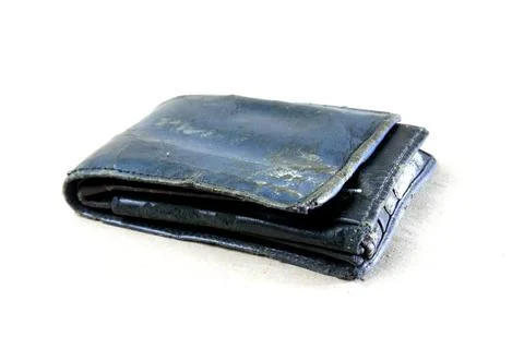 A close-up view of a worn, folded leather wallet resting on a white surface.. Stock-Fotos
