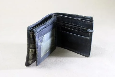 A close-up view of a worn, folded leather wallet resting on a white surface.. Stock-Fotos
