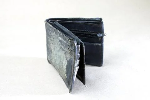 A close-up view of a worn, folded leather wallet resting on a white surface.. Stock-Fotos