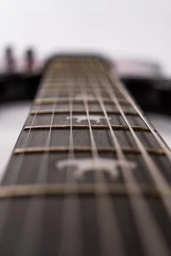 Close-up view of a worn modern electric guitar fretboard, strummed strings .. Stock Photos