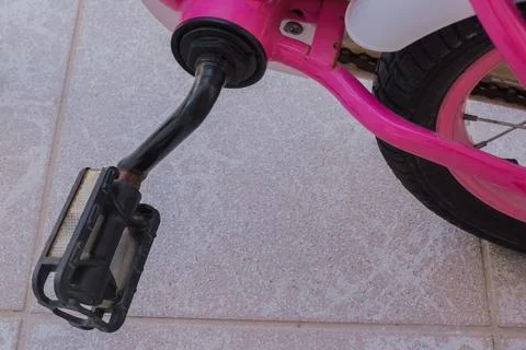 Close up view of worn rusty pedal attached to pink frame of children bicycl.. Stock Photos