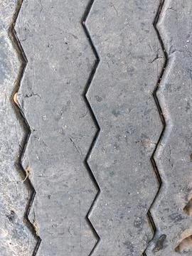 Close-up view of a worn tire surface featuring a zigzag groove pattern Stock Photos
