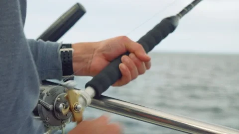 Close up view of yachtsman's hands trolling fish from board of yacht sailing in Stock Footage 87921199