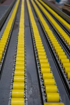 Close-up view of a yellow cylindrical object conveyor system in an industri.. Фото