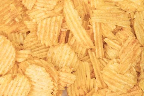 Close-up view of yellow potato chips in overlapping layers, gold brown color, Foto stock