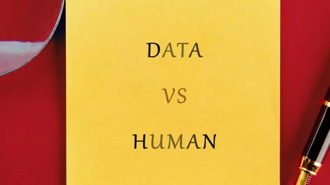 A close up view of a yellow sticky note with DATA VS HUMAN text. A magnifying Stock Footage 335079132