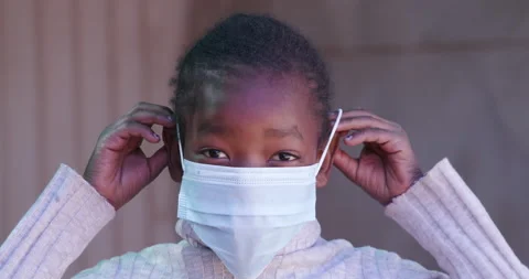 Close-up view of a young Black African girl putting on a mask Covid-19 Stock Footage 133919431