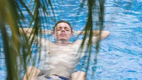 Close up view of a young Caucasian man lying and floating in water in the pool Stock Footage 149553371