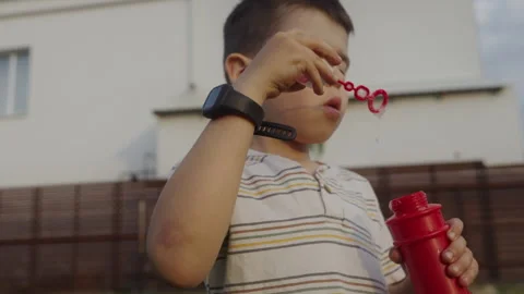 Close up view of a young child blowing colorful iridescent bubbles with a soap Stock Footage 247032627
