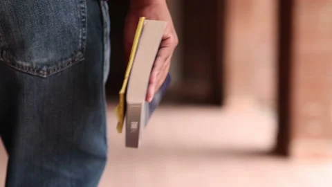 Close Up View Of Young Man Carrying Book and Notes In Hand While Walking Video stock 233457792