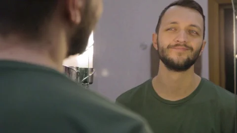 Close up view of young man looking at his reflection in a bathroom mirror  Stock Footage 104021792