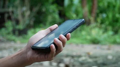 Close-up view of a young man in a park and using a smartphone. Stock Photos