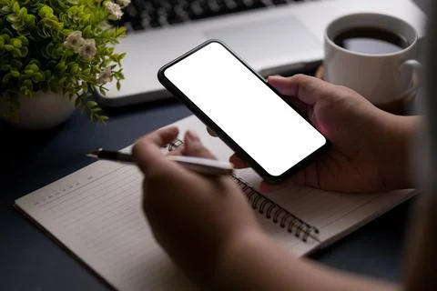 Close up view young man sitting at home office desk and using smart phone. .. Stock-Fotos