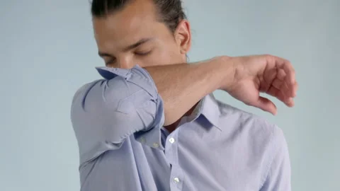Close up view of a young man sneezing and coughing to the elbow. Safe way Stock Footage 137773236