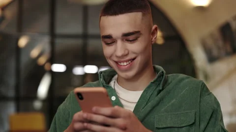 Close up view of young man with stylish haircut using smartphone while sitting Stock Footage 152134987