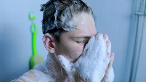 Close up view of a young man washing his face with foam in the home shower. Stock Footage 345531224
