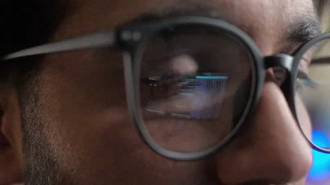 Close-up view of young man wearing glasses with reflection of screen with binary Video stock 228974299