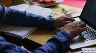 Close-Up View Of Young Man Writing Information Notes In Copybook Then Typing Stock Footage