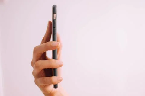 A close-up view of a young person's hand using a mobile phone on a white Fotos de archivo