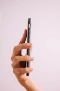 A close-up view of a young person's hand using a mobile phone on a white Stockfoto's