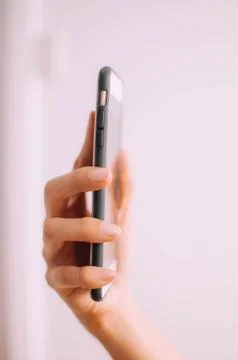 A close-up view of a young person's hand using a mobile phone on a white Stock-Fotos