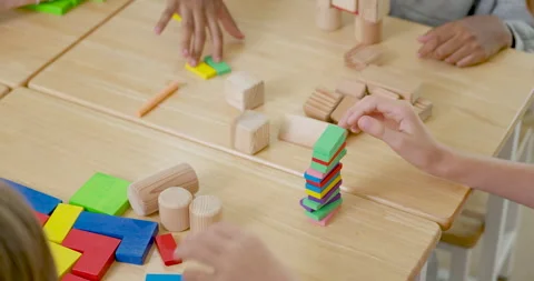 Close view of young pupils using hands to stack colorful tiles and wooden blocks Stock Footage 336065486