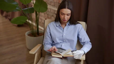 Close view of young woman with bionic prosthesis is reading book and sitting in Stock Footage 194498477