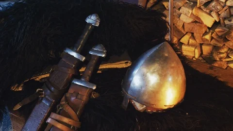 A close-up of a Viking helmet and two swords in a scabbard. Stock Footage 89625972