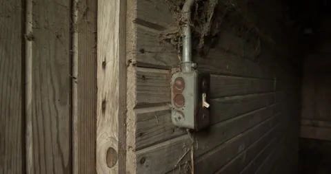 Close up of a vintage electrical switch mounted on a rustic wooden barn wall in Stock Footage 333184138