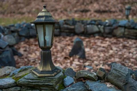 Close up of vintage lanterns on rustic stone outdoor space surrounded by dry Stock Photos